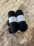 Two skeins of black Kangaroo Island Wool yarn.