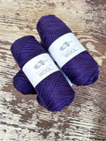 Two purple balls of Kangaroo Island Wool yarn on a wooden surface